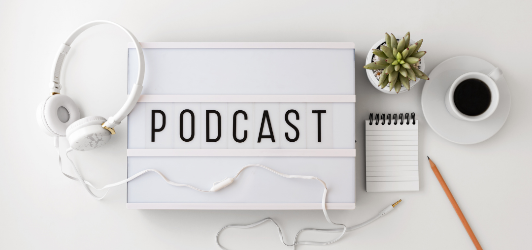 Høretelefoner, podcast, notesblok, plante og kaffe